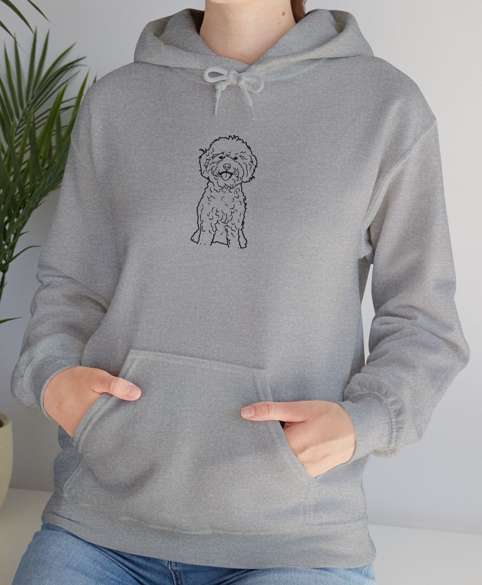 Person wearing a gray hoodie with a dog illustration in a home setting