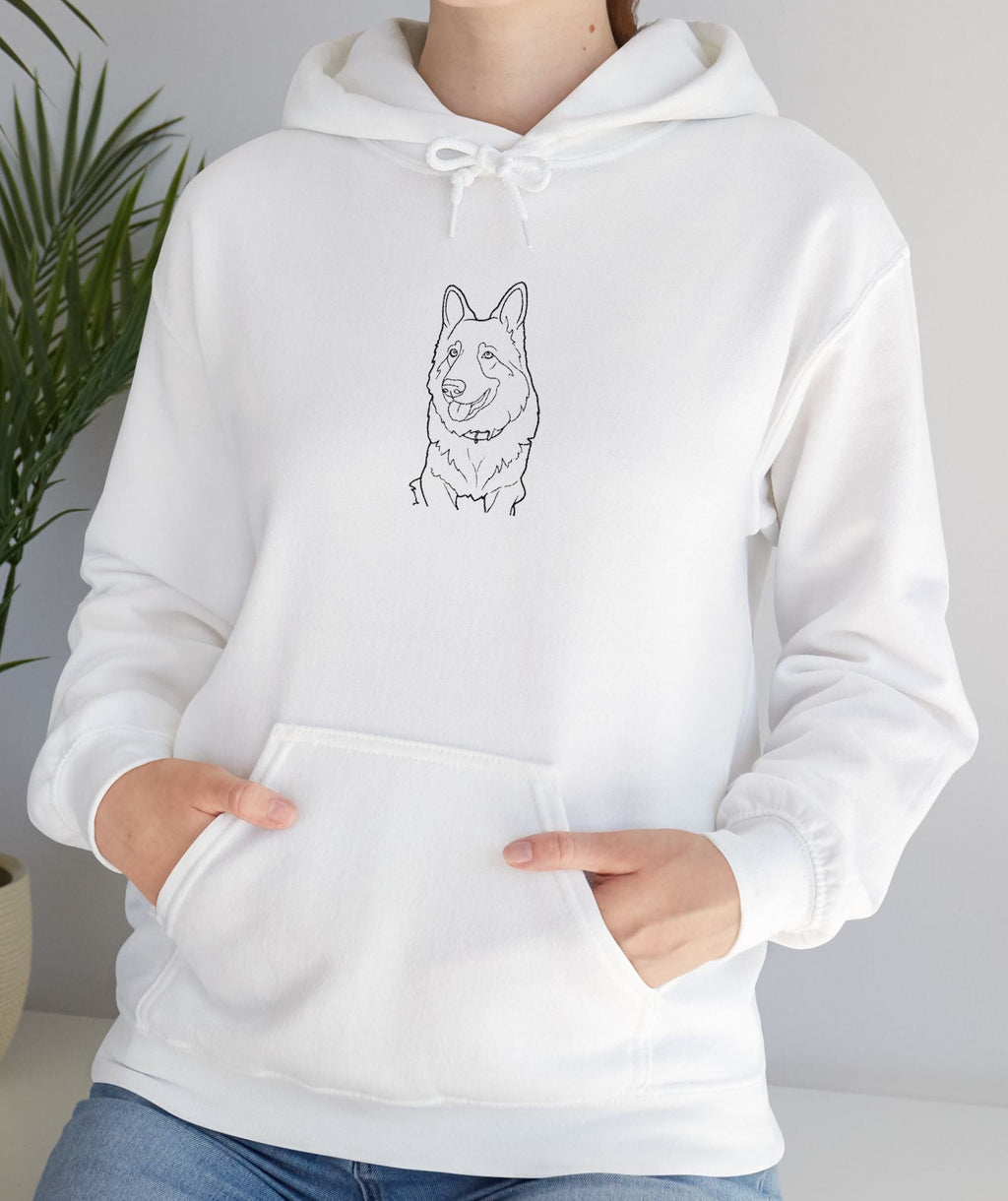 Person wearing a white hoodie with a dog illustration in a room with a plant.
