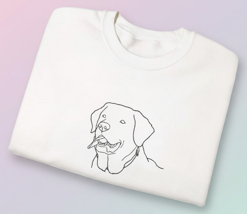 Folded white sweatshirt with a black line drawing of a dog on a pastel background