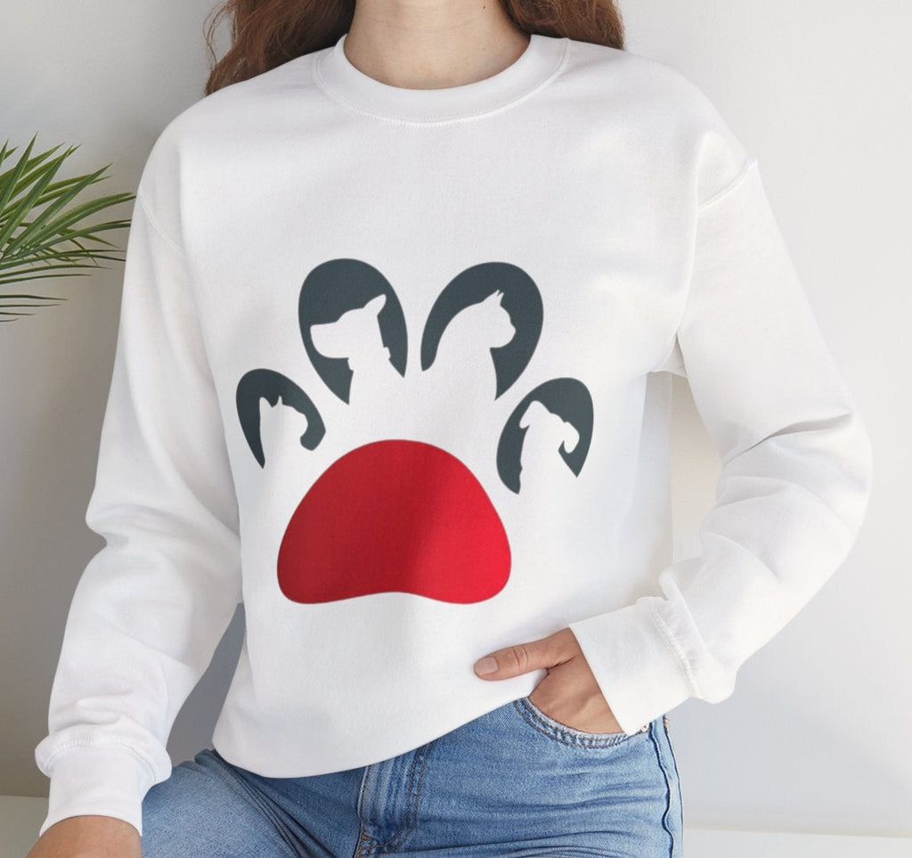 Woman wearing a white sweatshirt with a red and black paw design, sitting in a room with a plant.