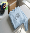 Folded light blue sweatshirt with a dog logo on an ironing board, with a Rottweiler photo inset.