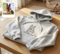 Folded gray hoodie with a dog illustration on a wooden table