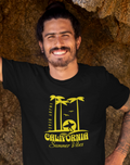 Man standing in a cave on a beach wearing a black t-shirt and blue shorts.