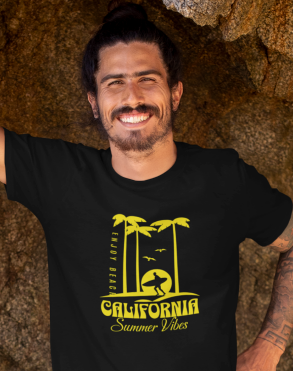 Man standing in a cave on a beach wearing a black t-shirt and blue shorts.